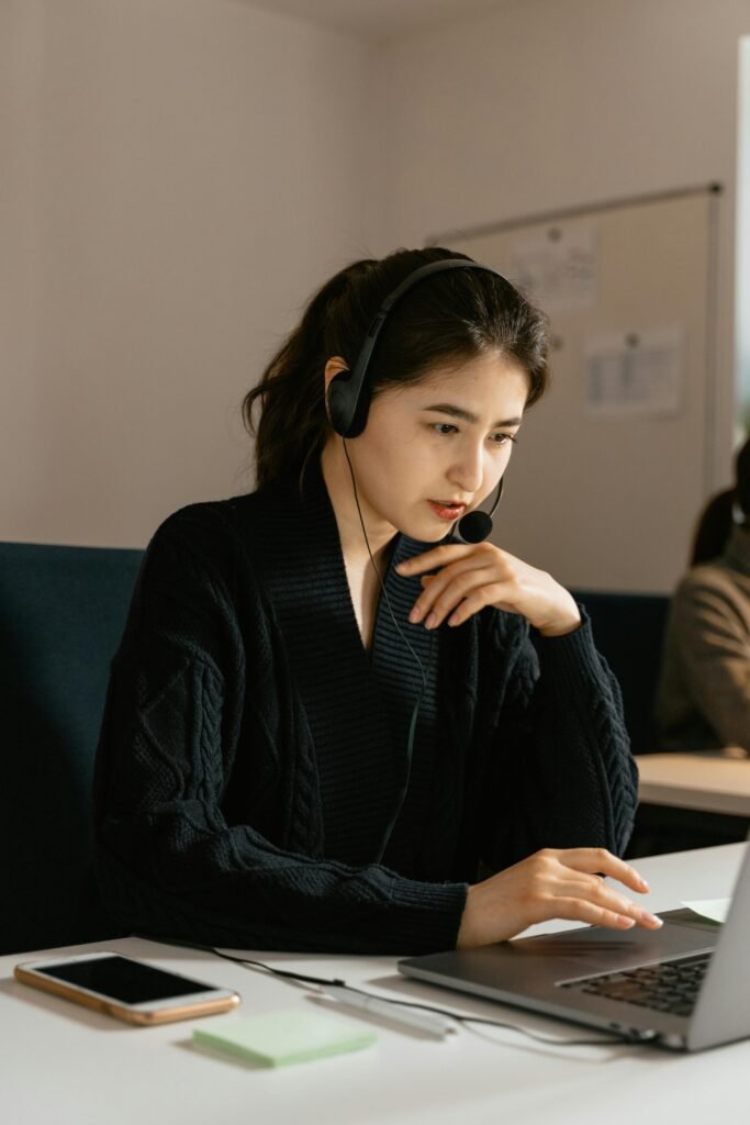 pexels-photo-7709291-7709291 Focused female customer support agent in an office using a laptop and headset.